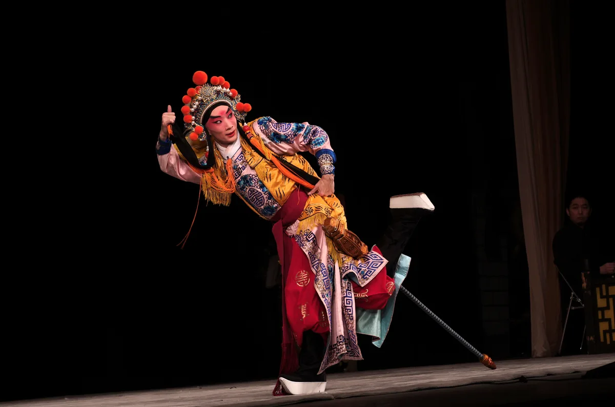 A Peking Opera performer in a dramatic acrobatic pose in elaborate costume